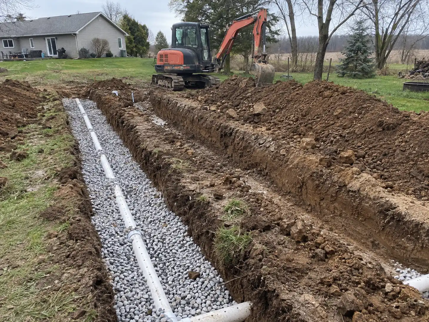 Excavator digging trenches for a leaching bed replacement